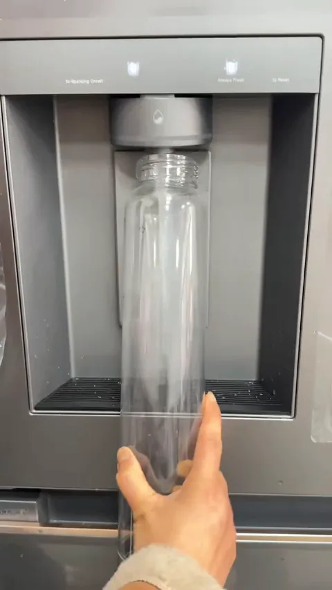Filling from the dispenser — the bottle lives in the fridge door.